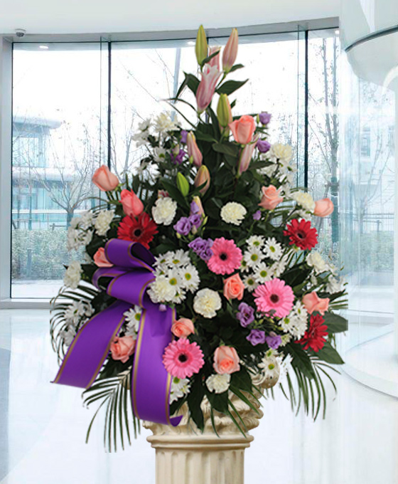 Centro de flores con gerberas rojas y rosas rosadas, margaritas y claveles y lisanthus